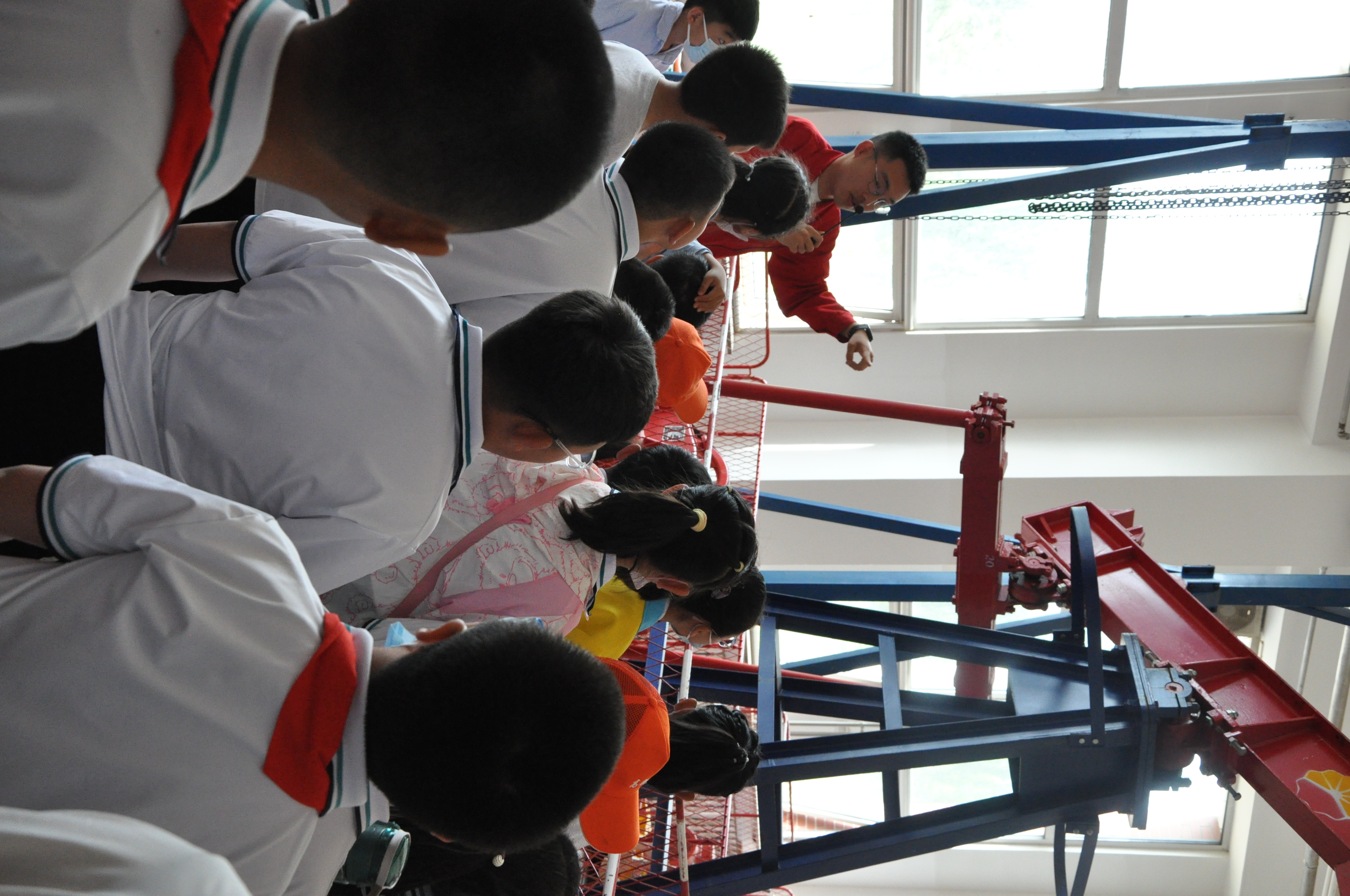 志愿者利用采油机设备为小朋友们讲解采油过程,让小朋友近距离观看采油设备(“磕头机”)。