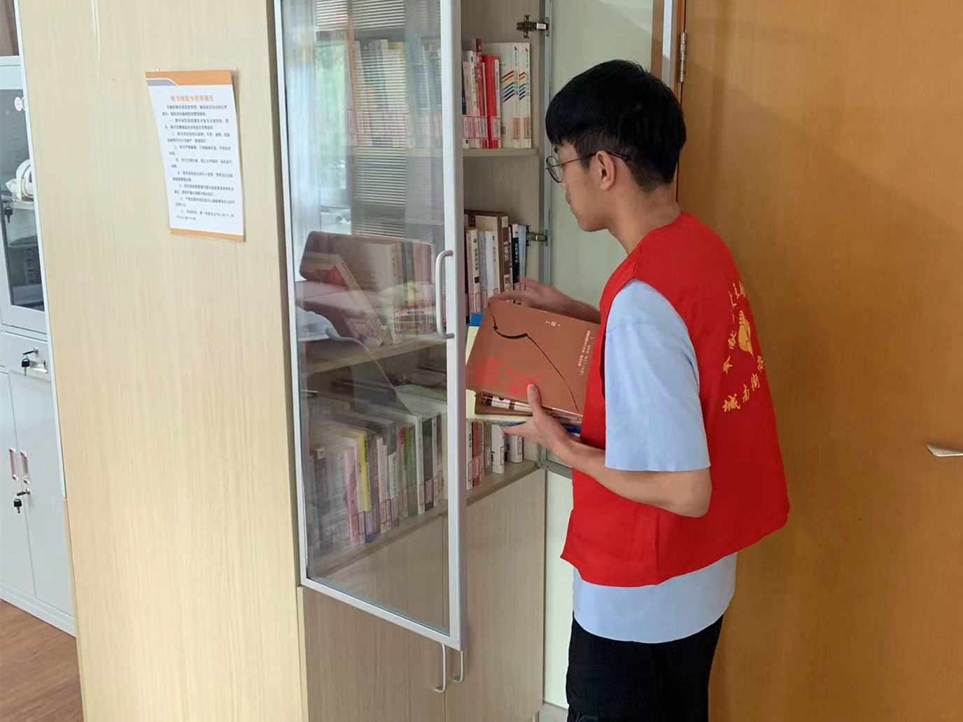 图为学生葛宇恒在江苏省苏州市张家港市城南街道参与社区新时代文明实践活动,为图书室提供卫生打扫、图书整理及借阅登记服务。