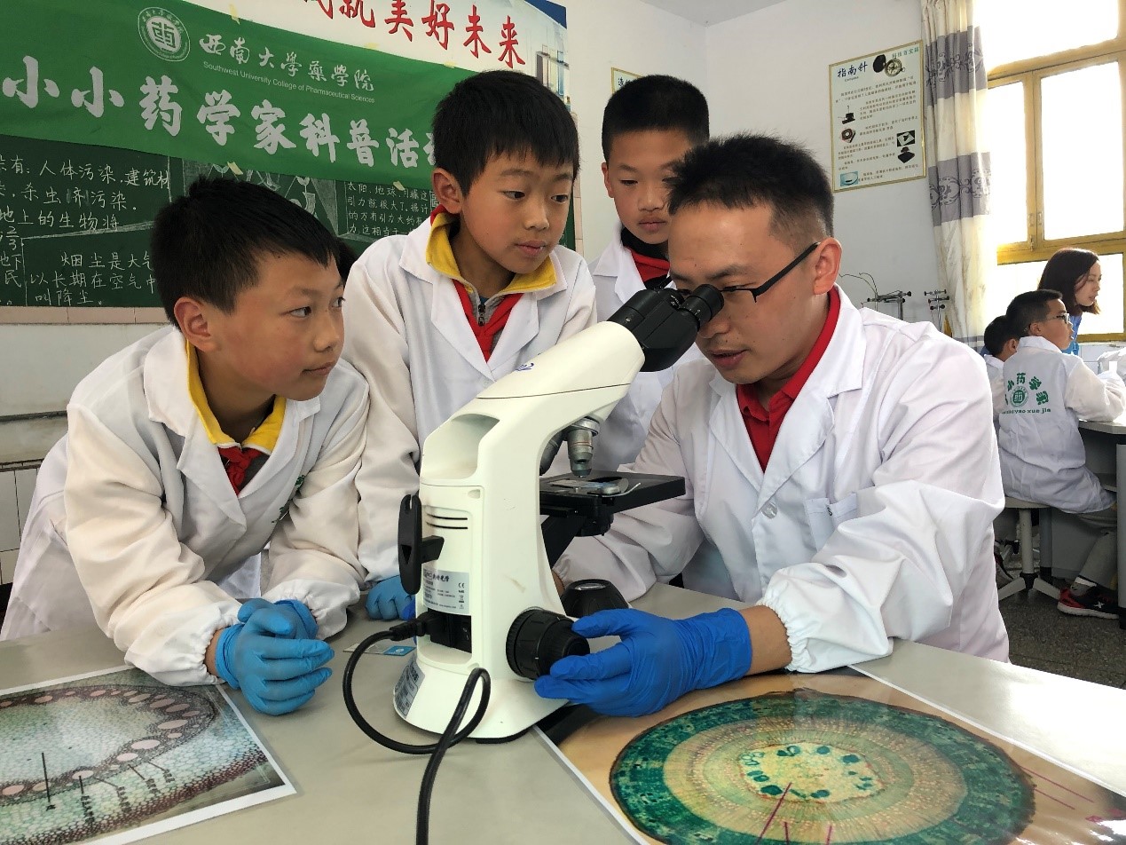 图1 支部尹国平老师正在指导黄水小学学生观察中药材切片.jpg